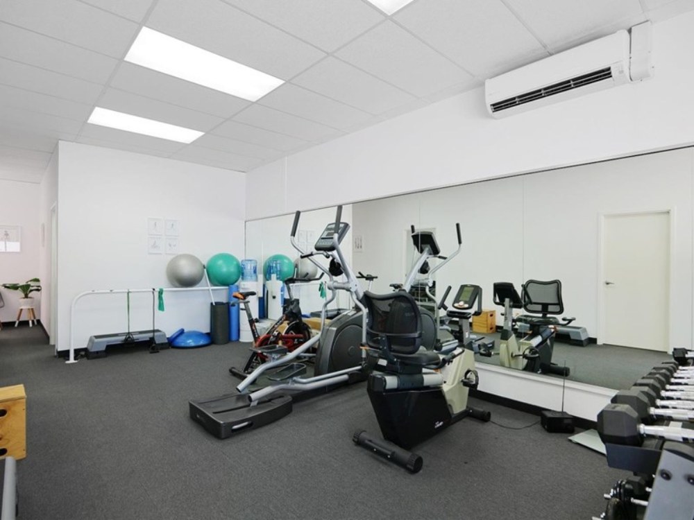 gym equipment in front of large mirror in medical building